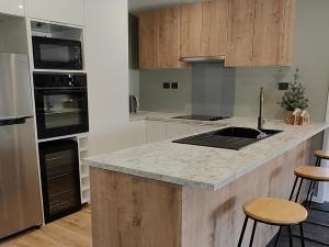 a kitchen with wooden cabinets and a counter with stools at Holiday retreat in the heart of old Cromwell! in Cromwell