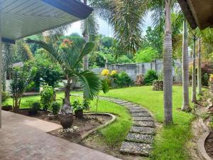 un jardin avec un palmier et une passerelle dans l'établissement Samal Island Garden Villa - Spacious 3BR, AC, Wi-Fi, Indoor-Outdoor Kitchens, à Caliclic