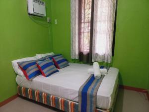 a bedroom with a bed with a green wall at Samal Island Garden Villa - Spacious 3BR, AC, Wi-Fi, Indoor-Outdoor Kitchens in Caliclic