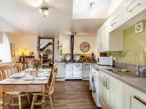una cocina con mesa y sillas y una cocina con armarios blancos. en 2 Bed in Chagford 89119, en Throwleigh