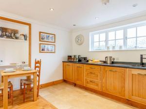 cocina con armarios de madera, mesa y reloj en 1 Bed in Bigbury-on-Sea 88098, en North Huish