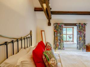 a bedroom with a bed with red pillows and a window at 2 bed in Ramsgill 89166 in Bouthwaite