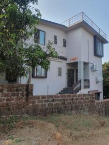 una gran casa blanca con una pared de ladrillo en Samarth Homestay, en Ratnagiri