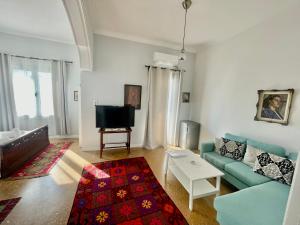 a living room with a blue couch and a tv at A litte Taste of Home Guest House in Athens