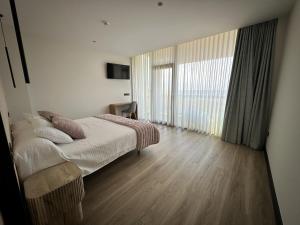 a bedroom with a bed and a large window at Hotel A Ladela in O Vicedo