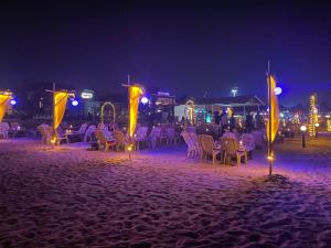 un grupo de mesas y sillas en una playa por la noche en Yellow Sky en Baga