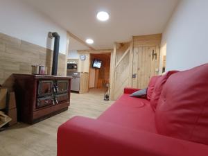 un sofá rojo en la sala de estar con fogones en Luční chalupa, en Velká Úpa