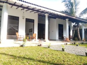a white house with a patio and a yard at Villa Conch by Om - Private House - Hikkaduwa in Hikkaduwa