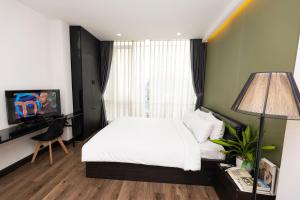 a bedroom with a bed and a desk and a television at The One Premium Hotel in Ho Chi Minh City