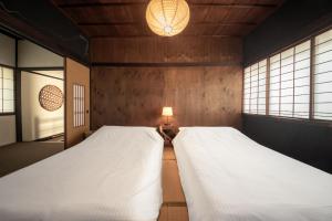 twee bedden in een kamer met twee ramen bij HISORI Arts and Stay in Kanazawa