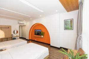 an orange and white room with two beds and a tv at The One Premium Hotel in Ho Chi Minh City