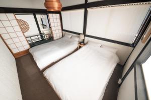 twee bedden in een kleine kamer met ramen bij HISORI Arts and Stay in Kanazawa