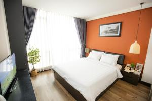 a bedroom with a bed with an orange wall at The One Premium Hotel in Ho Chi Minh City