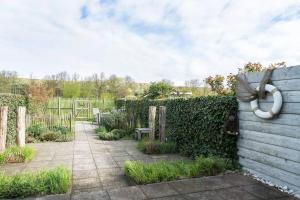 einen Garten mit einem Zaun mit einem weißen Schlauch darauf in der Unterkunft Lepelblad 17* in Nieuwvliet