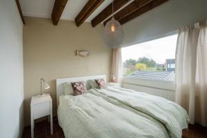 ein Schlafzimmer mit großem Bett und Fenster in der Unterkunft Lepelblad 17* in Nieuwvliet