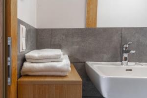 ein Badezimmer mit einem Waschbecken und einem Stapel Handtücher in der Unterkunft Naturdorf Oberkühnreit in Neukirchen am Großvenediger