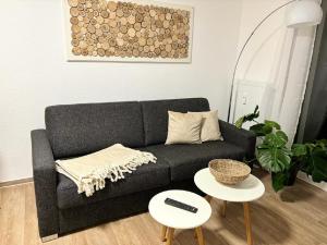 ein Wohnzimmer mit einem schwarzen Sofa und 2 Tischen in der Unterkunft Charming Homes - Studio 20 in Wolfsburg
