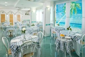 a dining room with white tables and white chairs at HOTEL AURORA in Cattolica