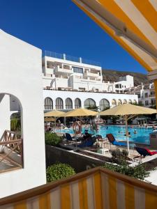 een uitzicht op een hotel met een zwembad en parasols bij Atlantic View Apartment Los Cristianos At Marysol Hotel Tenerife in Arona