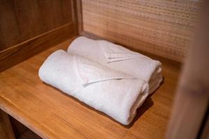 zwei weiße Handtücher auf einem Holztisch in der Unterkunft Three Beagles Villa in Ubud
