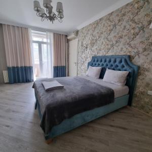 a bedroom with a large bed with a blue headboard at ApartHotel city centrum in Chişinău