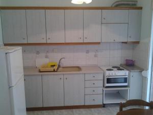 a kitchen with white cabinets and a sink and a stove at Esperides Villas in Fourka