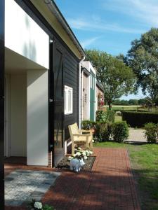 un gato blanco sentado en un patio de ladrillo junto a una casa en het Neerland, en Biggekerke