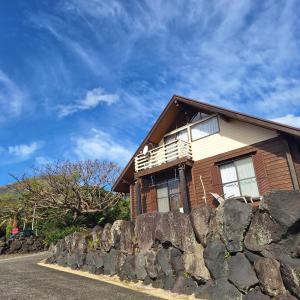 uma casa no topo de uma parede de pedra em 八丈島メープルハウス em Hachijo