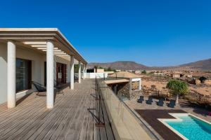 a house with a wooden deck with a swimming pool at Villa Atlanntes con piscina en Fuerteventura in Triquivijate