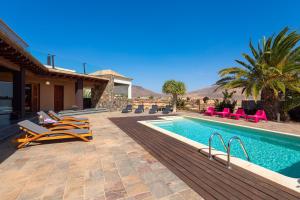 a swimming pool with chairs and a house at Villa Atlanntes con piscina en Fuerteventura in Triquivijate
