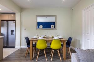 4 Bed Terraced House in Beeston with Convenient City Centre Access في نوتينغهام: غرفة طعام مع طاولة خشبية وكراسي صفراء