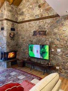 sala de estar con pared de piedra y TV de pantalla plana. en Villa Gjelbër 1 en Prizren