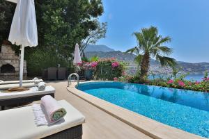 a swimming pool with a table and an umbrella at Stunning Seaviews in Kalkan