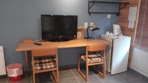 a computer desk with a television and a refrigerator at Hotel restaurant la terrasse du mont bar hotel leydier in Allègre