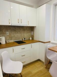 a kitchen with white cabinets and a white chair at CozyApartment14 in Roşu