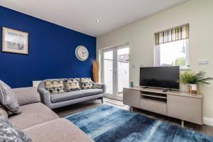 uma sala de estar com um sofá e uma televisão de ecrã plano em 4 Bed Terraced House in Beeston with Convenient City Centre Access em Nottingham