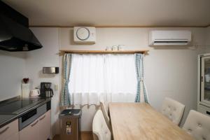 a kitchen with a table and a clock on a window at おもや彩OmoyaSai-天然温泉付き貸別荘1棟貸し in Kirishima