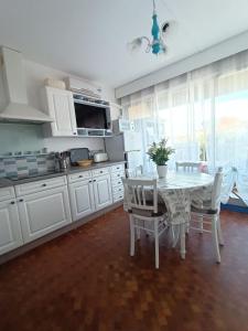 eine Küche mit einem weißen Tisch und Stühlen sowie eine Küche mit einem Fenster in der Unterkunft Fleur Australe in Gruissan