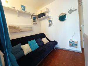 ein Wohnzimmer mit einem schwarzen Sofa und Kissen in der Unterkunft Fleur Australe in Gruissan