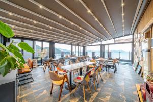ein Restaurant mit Tischen und Stühlen und großen Fenstern in der Unterkunft Le Paradis Ocen view Spa Pension in Yeosu