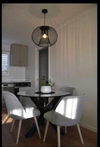 uma mesa de jantar com cadeiras brancas e um lustre em Inspire Boutique Apartments em Devonport