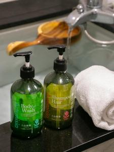 2 botellas de detergente para ropa sentadas en el lavabo del baño en King Hot Spring Hotel, en Jiaoxi
