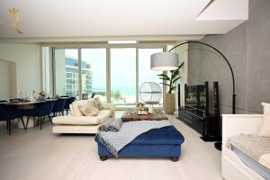 a living room with a blue ottoman in the middle of a room at 1BR Loft Soul Beach Escape - Mamsha Al Saadiyat in Abu Dhabi