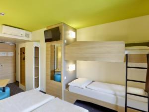 een kamer met 2 stapelbedden en een kamer met een tv bij B&B Hotel Trier in Trier
