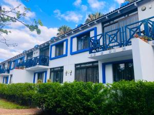 a white building with blue windows and bushes at Elephant Springs Apartments in Bela-Bela