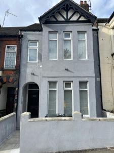 uma casa cinzenta com janelas brancas numa rua em 339 High Town Road em Luton