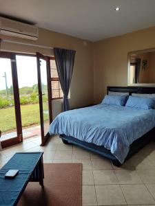 a bedroom with a bed and a table and a window at Ocean View Villas - F6 in Port Edward