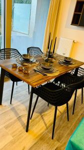 - une table en bois avec des chaises, des assiettes et de la vaisselle dans l'établissement Le Cocon, à Embourg
