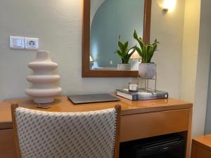 a desk with a mirror and a laptop and a vase on it at El Greco Hotel in Heraklio Town