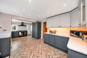 a kitchen with white cabinets and a wooden floor at Finest Retreats - Moorfield House in Bishop Thornton